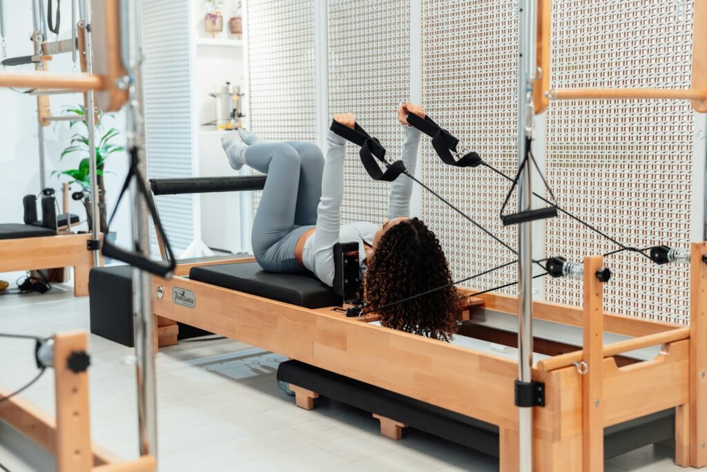 Certified Pilates instructor leading a personalized reformer Pilates session in a modern wellness studio.