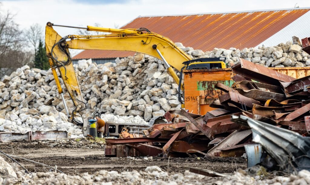 Construction debris removal crew clearing wood, drywall, and demolition waste from an active construction site using dumpsters and hauling equipment.