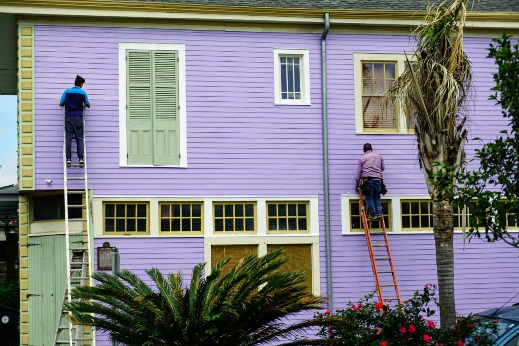 Professional exterior house painter applying weather-resistant paint to a home exterior to improve curb appeal and protect property value.