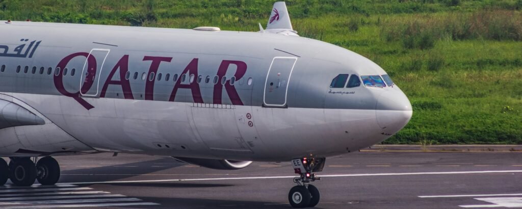 Passenger relaxing in Qatar Airways Business Class Qsuite with lie-flat seat and luxury cabin amenities.
