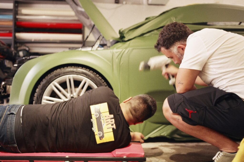 Professional auto body technician spray painting a modern car inside a paint booth, illustrating how much it costs to paint a car in 2026.