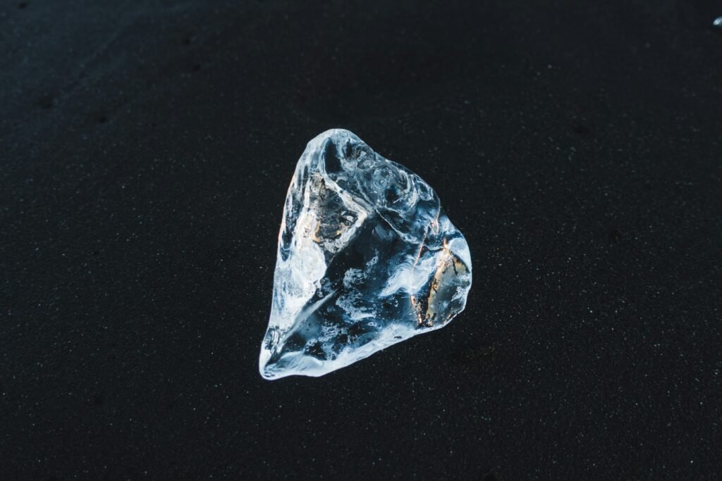 Raw diamond crystal beside common stones showing key visual differences used to identify an uncut diamond in nature.