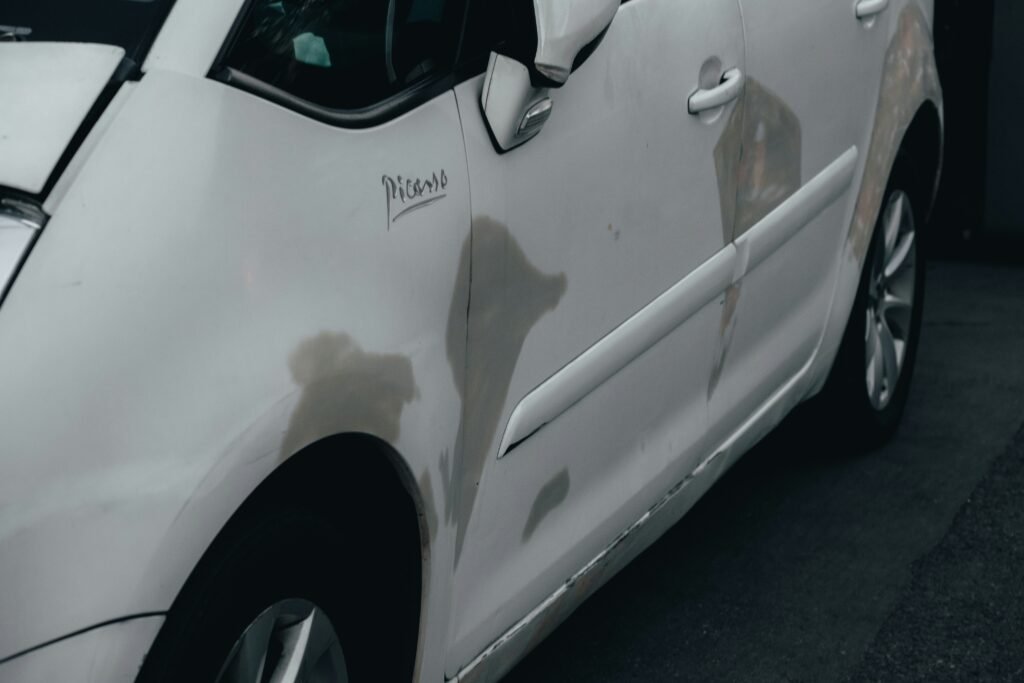 Technician performing paintless dent repair on a vehicle door using specialized tools to remove dents without damaging the factory paint.